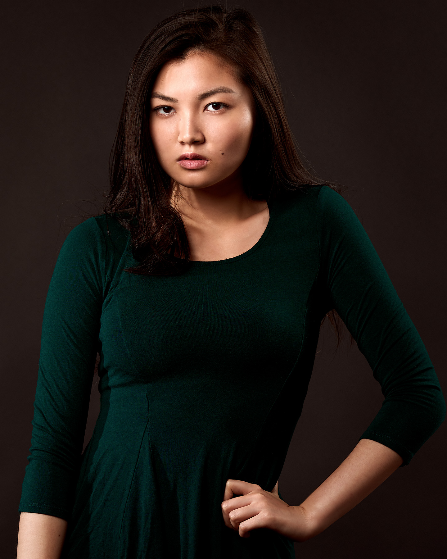 A woman posing against a dark background for modeling portfolio shots in Los Angeles
