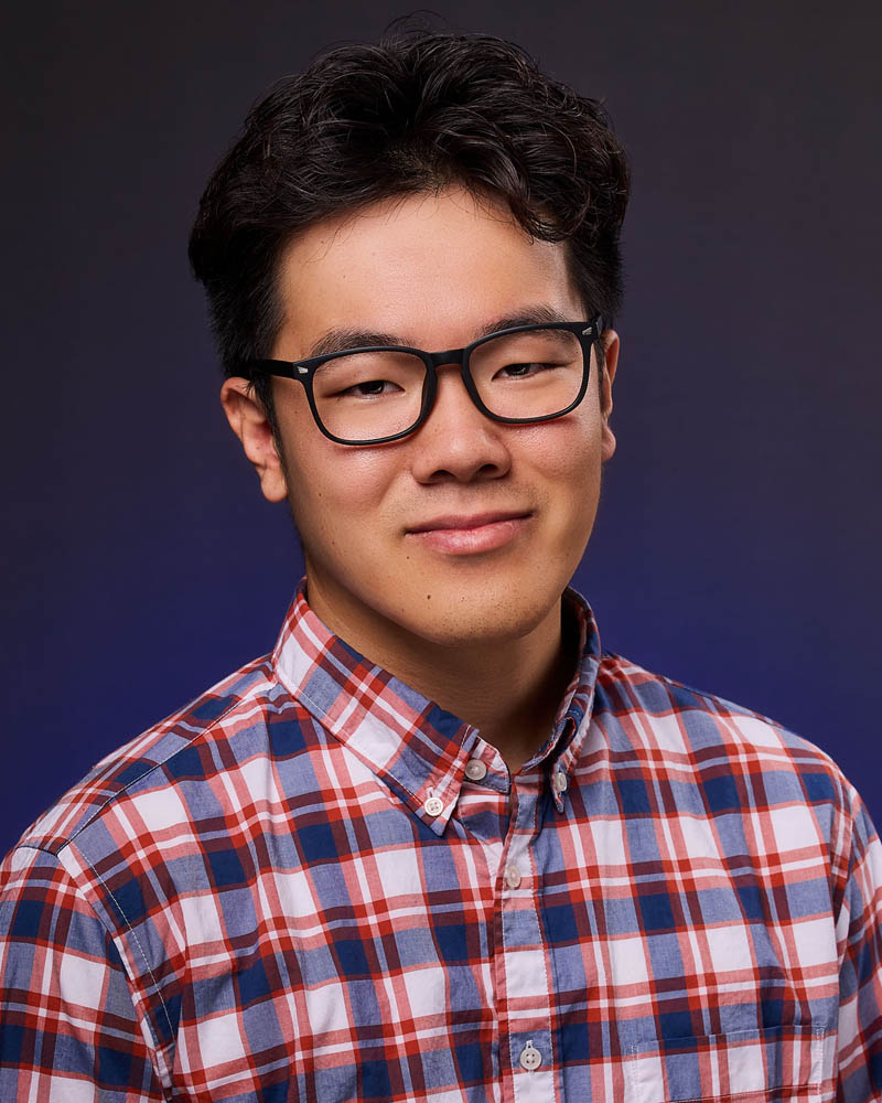A commercial actor headshot of an Asian man in a studio near Burbank with a blue background