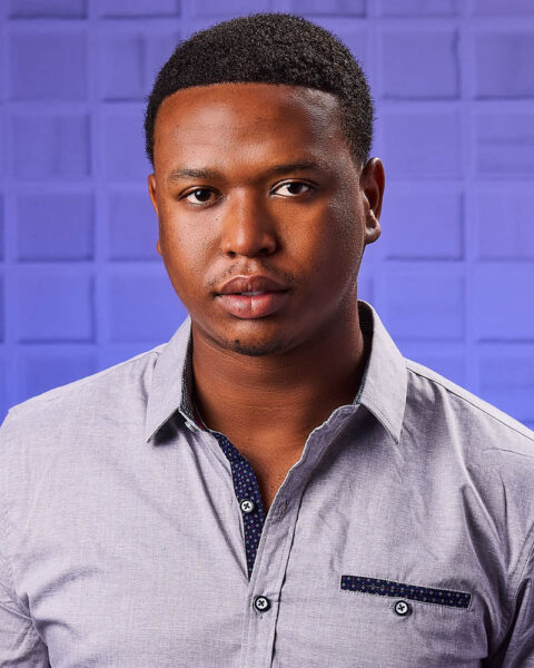 A commercial actor headshot of a black man in a studio near Burbank with a blue subway background