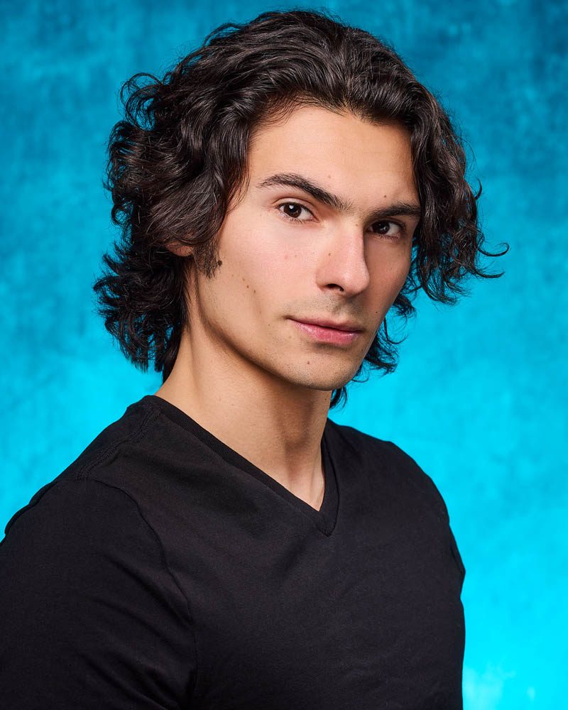 A commercial actor headshots of a man with a teal background wearing a black t-shirt made near Pasadena, CA