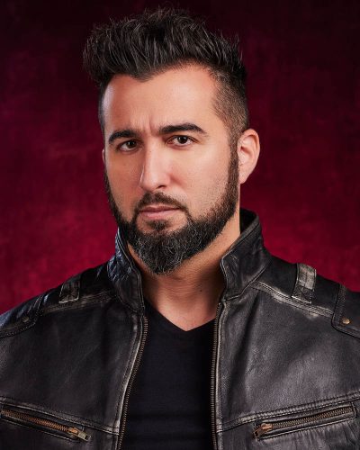 A theatrical actor headshot of a man in leather in a studio near Burbank with a red background