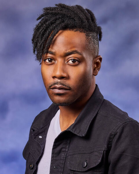 A theatrical actor headshot of a black man in a studio near Los Angeles with a blue background