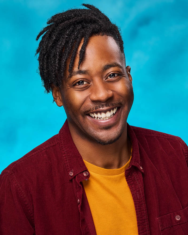 A commercial actor headshot of a black man in a studio near Los Angeles with a teal background